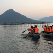 Team building by rafting in group at sunset on water